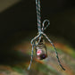 Small glass bottle with a scroll message and glitter inside tied to a string against a blurred natural background