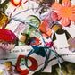 Colorful decorative items including flowers, ribbons, and small bottles on a textured surface.